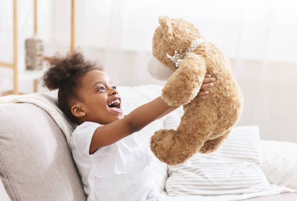 istock Joyful Child Playing With Teddy Bear in a Cozy Living Room Setting 2194369978