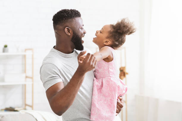 Father and Daughter Sharing a Joyful Dance in a Bright Room During a Sunny Afternoon