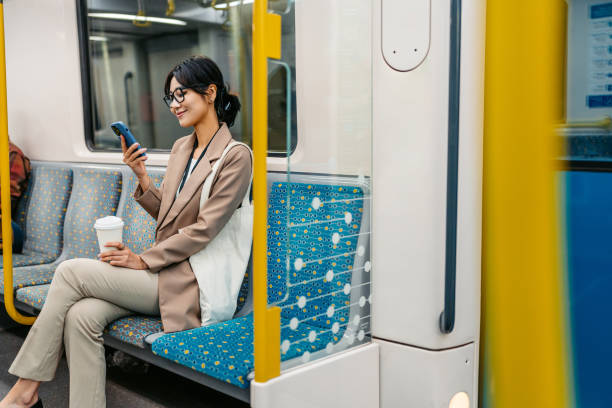istock Young Asian Businesswoman Using Phone And Drinking Coffee To Go While Riding In A Subway Train In Sydney In Australia 2194370001
