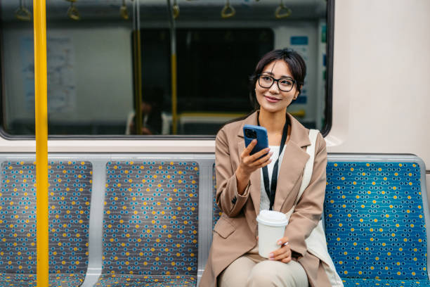 istock Young Asian Businesswoman Using Phone And Drinking Coffee To Go While Riding In A Subway Train In Sydney In Australia 2194370168