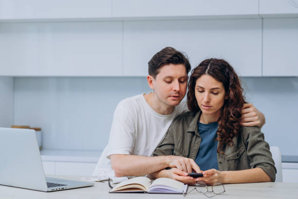 istock Married couple counting finances on calculator while sitting in kitchen at home 2194371041