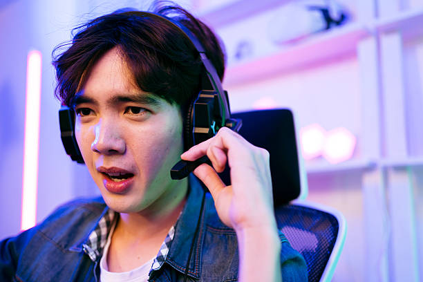 istock A focused gamer wearing a headset, engaged in gameplay, surrounded by colorful LED lights. A young gamer wearing a headset is actively engaged in gaming. Esports concept 2194371908
