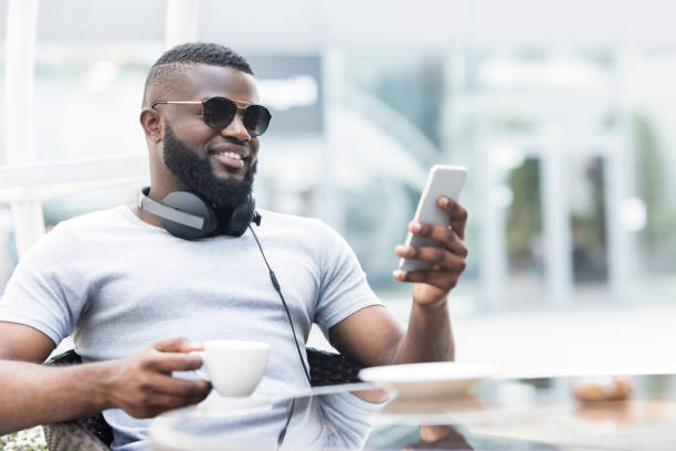 istock Young Man Enjoying Coffee While Using Smartphone in Outdoor Cafe During Daytime 2194371991