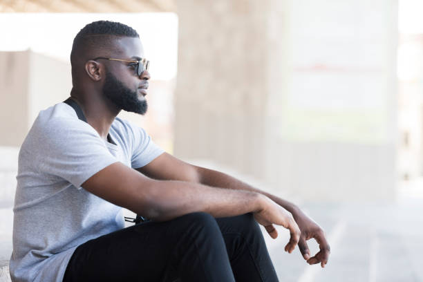 istock Man Sitting Quietly in a Modern Urban Space During the Day With Sunglasses On 2194372009