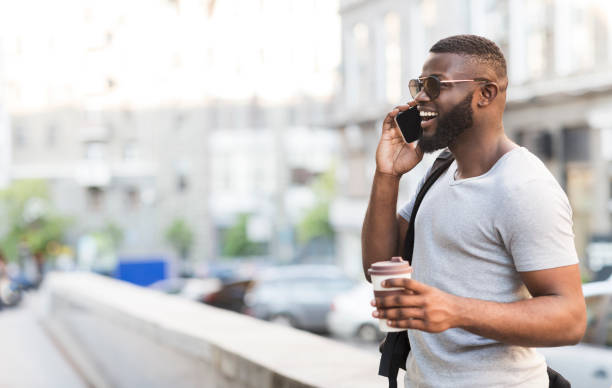 istock Man Enjoying Coffee While Talking on Phone in Urban Setting During Sunny Day 2194372026