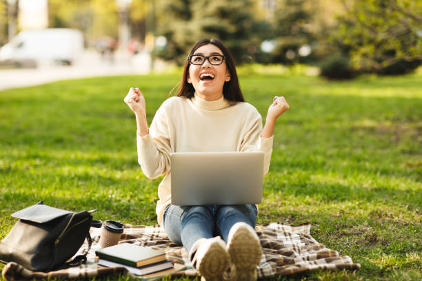 istock Young Woman Celebrates Success While Working on Laptop Outdoors in a Sunny Park 2194372170