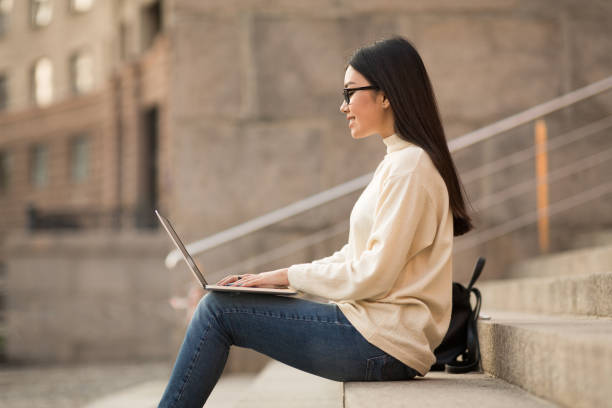 istock Young Woman Working on Laptop While Sitting on Outdoor Steps During Daylight 2194372248