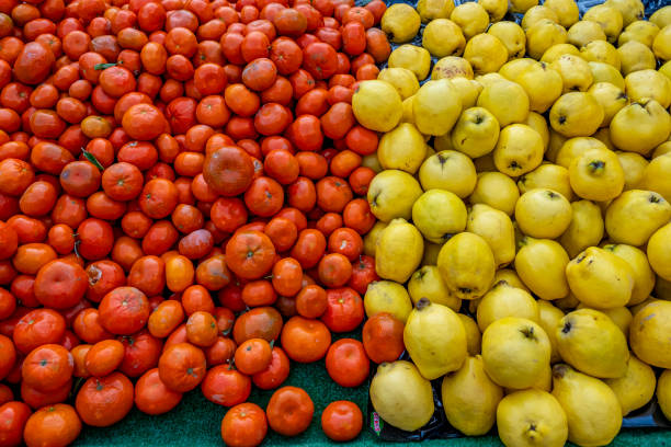 A tightly packed arrangement of vine-ripened tomatoes showcases their glossy red skin and natural imperfections, emphasizing freshness and authenticity at a farm stand. Keywords: tomatoes, close-up, red, fresh vegetables, ripe, farmers market, produce, healthy eating, organic food, seasonal harvest.