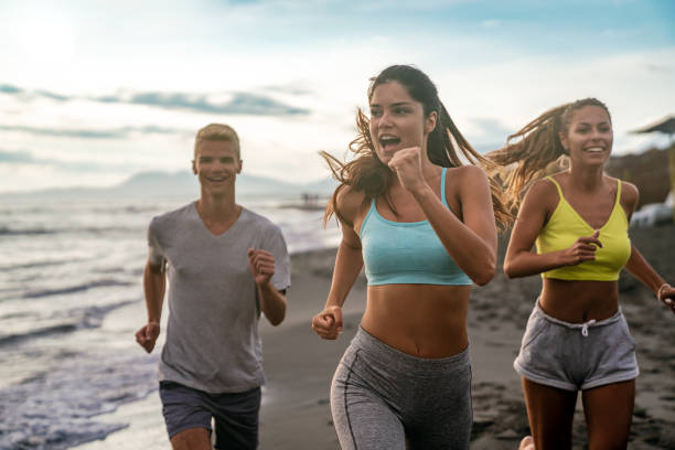 Group of athletes running uphill on a dirt road during a vibrant sunset, training together outdoors and embracing the spirit of teamwork