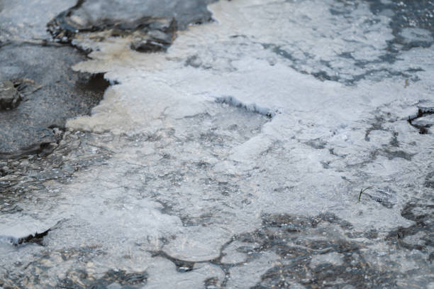 A detailed close-up of ice formations on the surface of a frozen water body. The textured layers and translucent ice capture the cold and intricate beauty of winter.