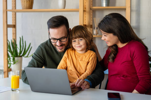 istock Parents and child relaxing at home with computer watching funny internet video, making online call 2194377216