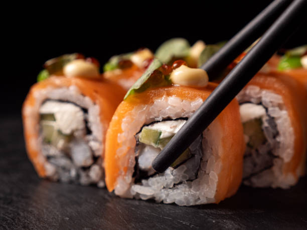 istock Japanese cuisine. Eating sushi roll with chopsticks 2194379834
