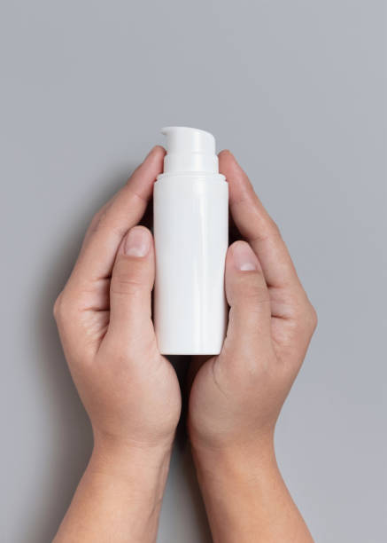 istock Female hands holding white cosmetic one pump bottle over grey top view, mockup, copy space 2194380083