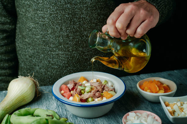 man dresses with olive oil a broad bean salad