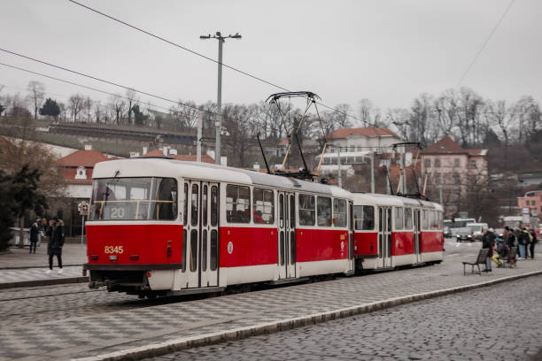 Prague, Czech republic - January 24, 2023: Red and white tram waiting at a station in prague, with passengers waiting to board