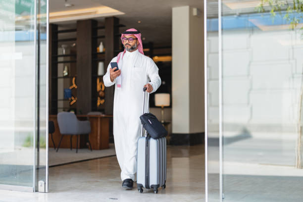 Middle Aged Arabic Businessman Exiting Hotel with Smartphone