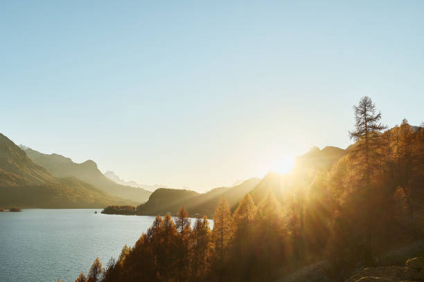 istock Landscape with large mountain lake, turquoise water. Golden fall trees with mountain. Last rays of sunlight from the sunset 2194385799