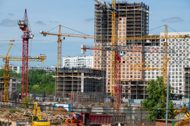 Tower cranes in close-up on the background of a multi-storey building under construction