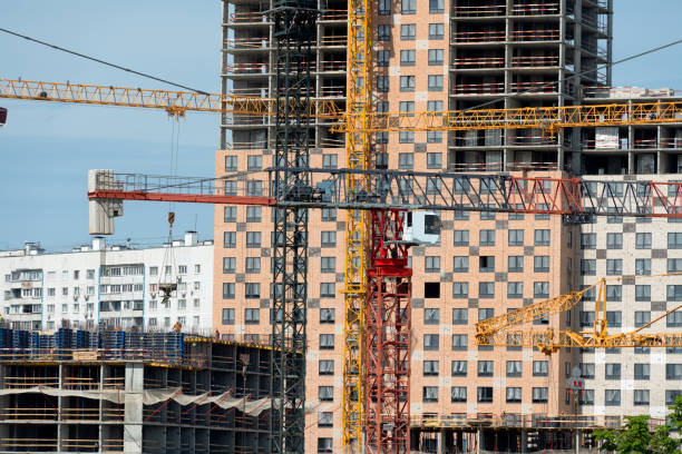 Tower cranes in close-up on the background of a multi-storey building under construction