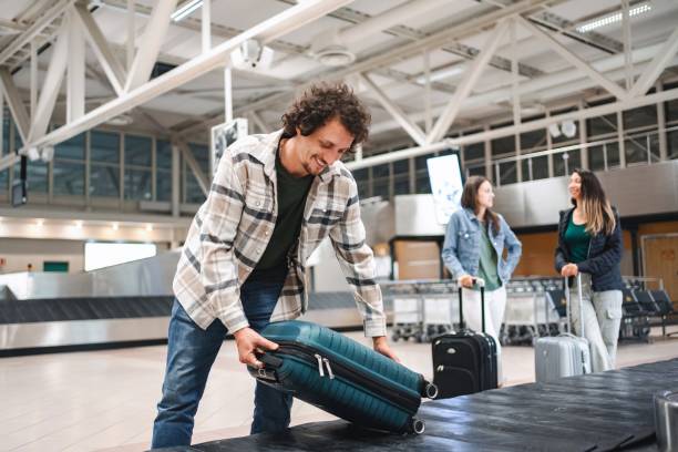 istock Young man picking up suitcase from airport baggage claim conveyor belt 2194387820