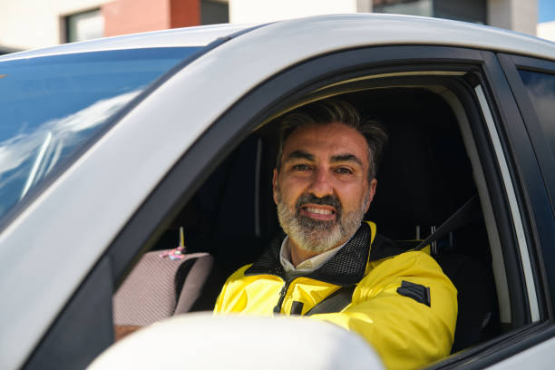 istock Smiling delivery man driving a car looking at camera 2194388681
