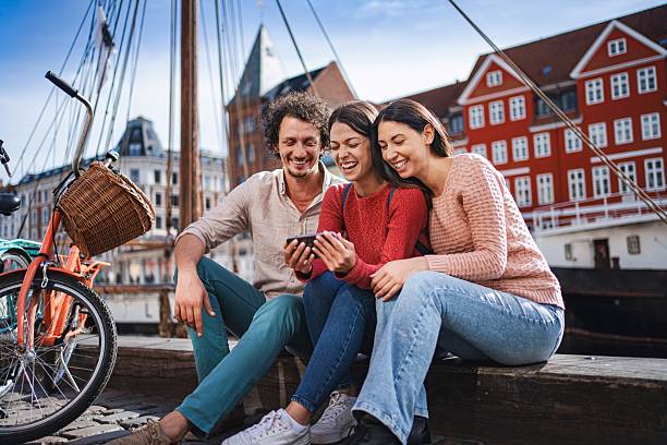 istock Tourists laughing while looking at smartphone in nyhavn, copenhagen 2194389136