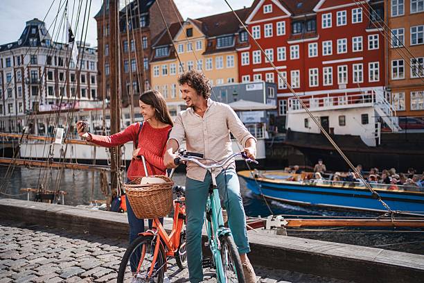 Happy couple taking a selfie while cycling in nyhavn, copenhagen, denmark