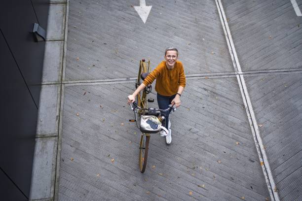istock Smiling woman walking with her bicycle in an urban setting 2194390068