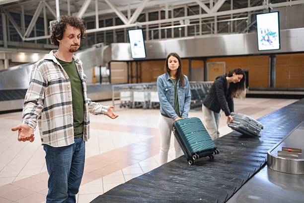 istock Man waiting for luggage at airport baggage claim carousel while other passengers are picking up their suitcases 2194391734