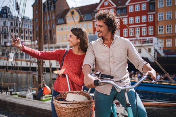 Happy couple taking a selfie while enjoying their bike ride in nyhavn, copenhagen