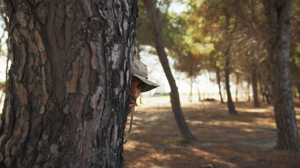 Scared Soldier Hides Behind A Trunk Of Tree From The Enemy's Imminent Attack