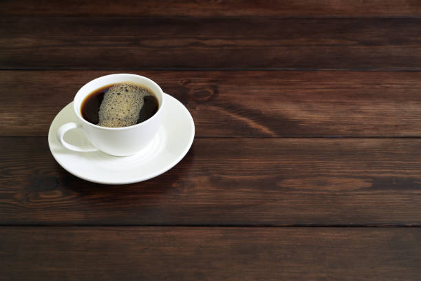Porcelain Coffee Cup with Frothy Black Coffee on Rustic Wooden Table