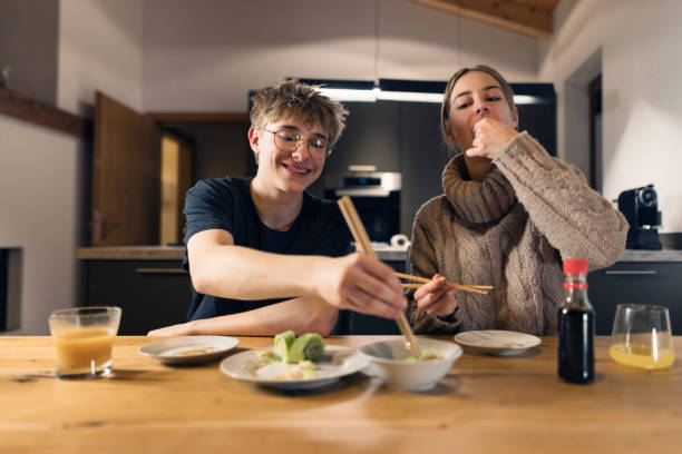 istock Teenagers eating cucumber and salmon rolls in a modern kitchen 2194395445