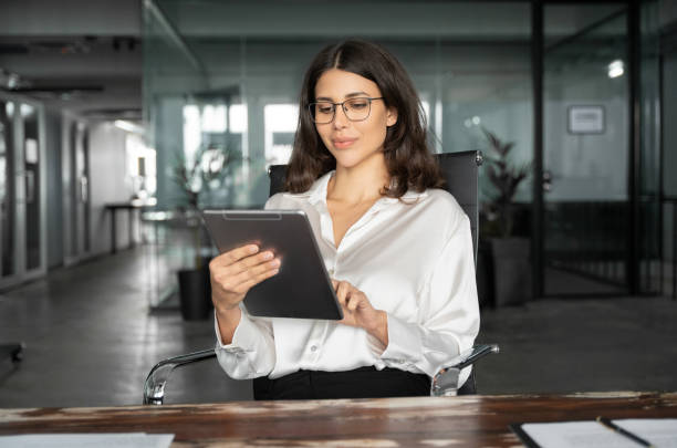 istock Middle eastern businesswoman holding digital tablet using tab application sitting at desk workplace in office. Young latin Hispanic professional business woman working on touchscreen pad pc computer. 2194397194