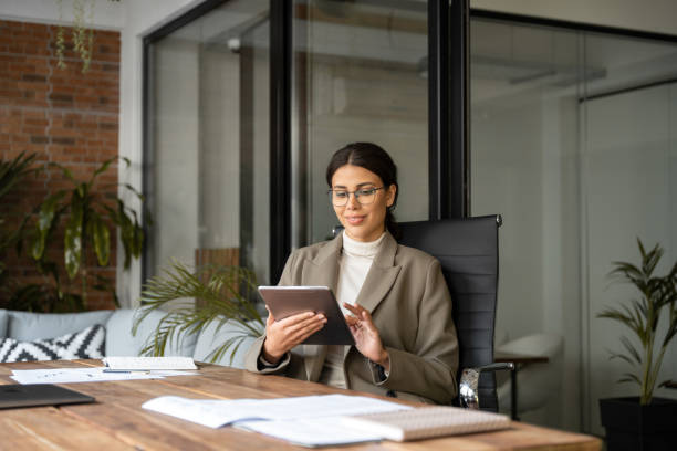istock Young latin Hispanic professional business woman working on pad pc computer. Middle eastern businesswoman holding digital tablet using tab application sitting at desk workplace in office. Copy space 2194397217