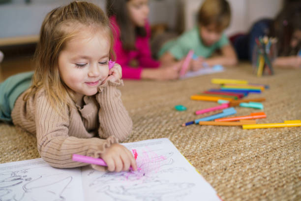 istock Little girl coloring with crayon while lying on a carpet 2194397818