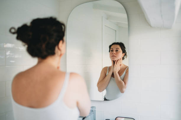 istock Woman checking her neck in the bathroom mirror 2194400392