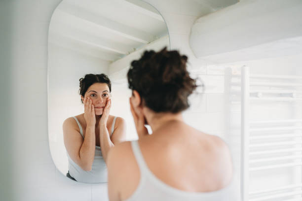 istock Woman checking her face in the bathroom mirror 2194400460
