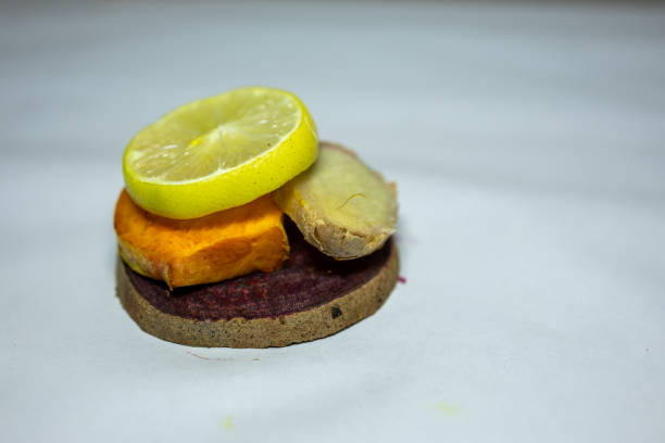 slice of fresh raw turmeric, beetroot, lemon and ginger in studio on blurred white background