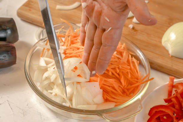 istock Chef adds chopped onion to grated carrots. Close-up 2194403210