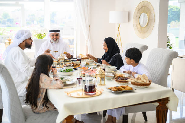 istock Three generation Emirati family sitting at dining table celebrating Eid-Ul-Fitr, smiling and laughing 2194403611