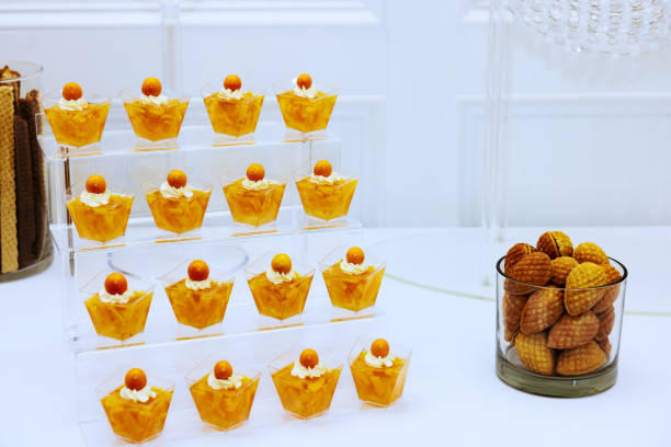 Refined dessert arrangement showcases small cups filled with cream topped by orange sweets cookies perfect for celebratory occasions.