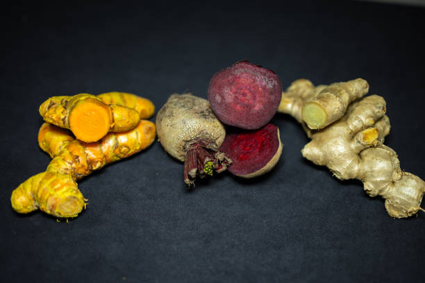 fresh raw turmeric, beetroot, and ginger in studio light shot on black background