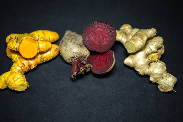 fresh raw turmeric, beetroot, and ginger in studio light shot on black background