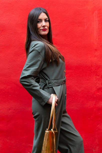 istock Fashion model posing with gold bag and red background 2194412146