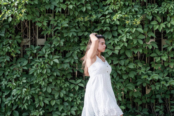 Young beautiful smiling woman in Virginia creeper leaves in spring . Copy space. Outdoor shot