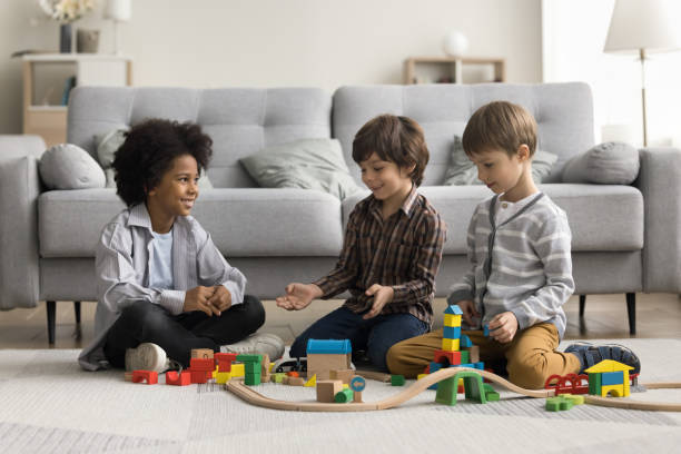 istock Three cute multiethnic boys play wooden railway at home 2194418978