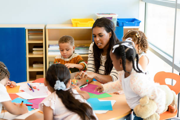 istock Teacher Assisting Preschool Students with Arts and Crafts Project 2194423048