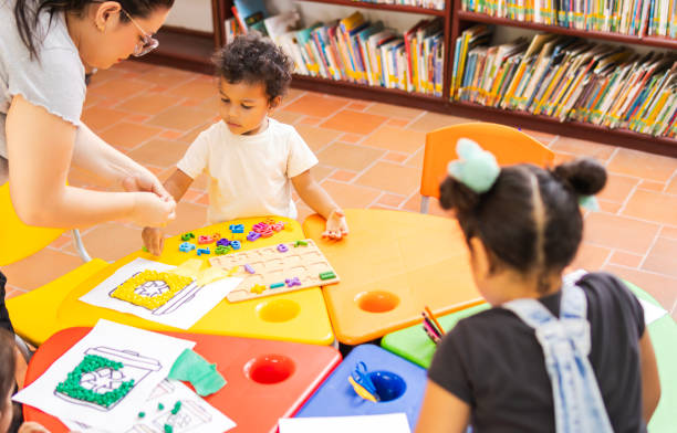 istock Teacher helping preschool children playing with numbers in library 2194427655