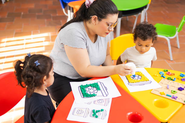 istock Teacher helping children with recycling activities in kindergarten class 2194427819